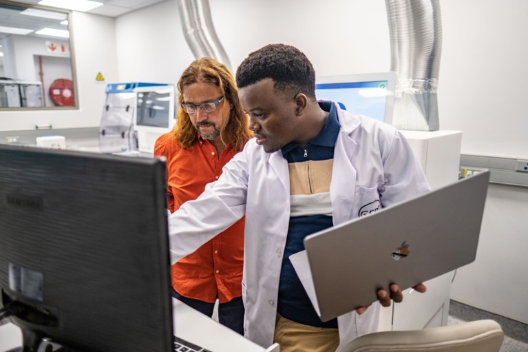 Tulio de Oliveira and Dr Wonderful Tatenda Choga look at a computer in a laboratory