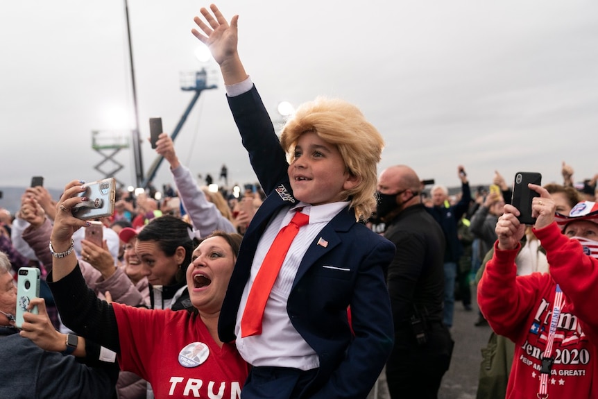 Supporters, including a child in a Trump costume, cheer as President Donald Trump arrives to speak at a campaign rally