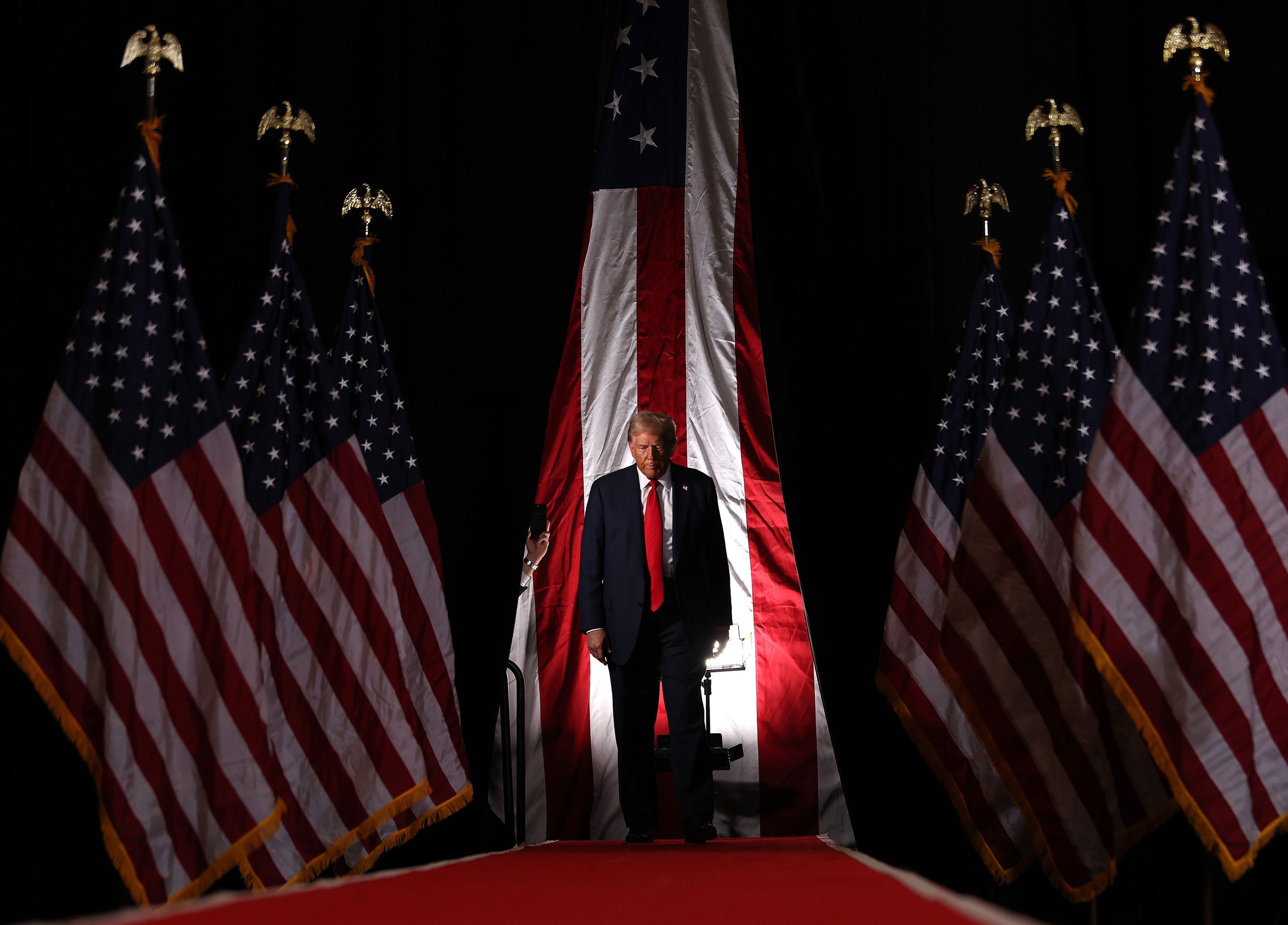 Donald Trump surrounding by American flags