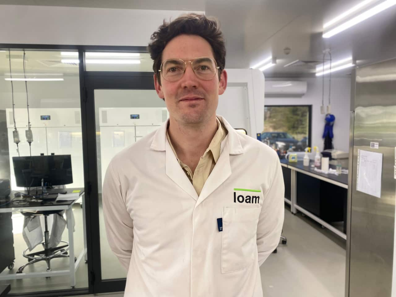 A man wearing a white labcoat standing in a laboratory