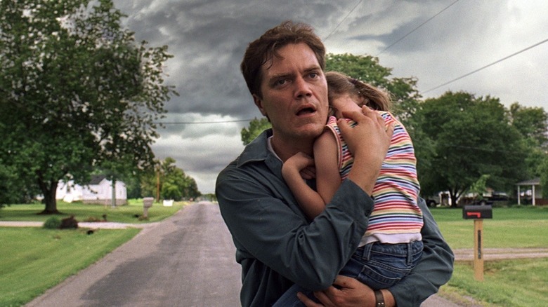 Curtis holds his daughter and looks shocked in Take Shelter