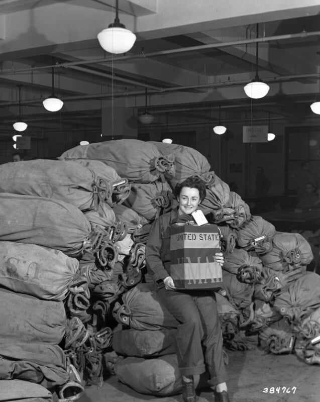 A person smiling and holding a large sack labeled 