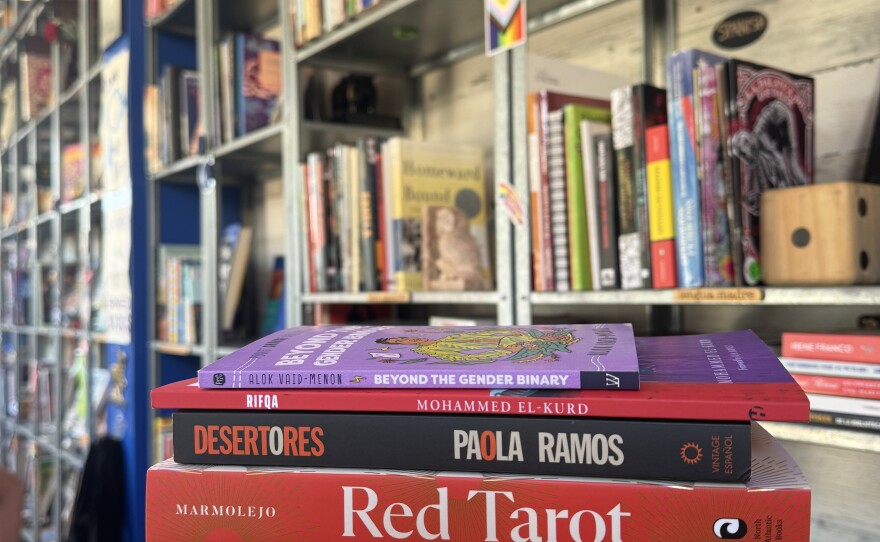 A stack of books are held up in this photo taken at Libélula Books & Co., Dec. 13, 2024.