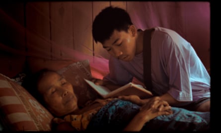 A young man reads to the Tibetan Book of the Dead to an elderly woman in bed.