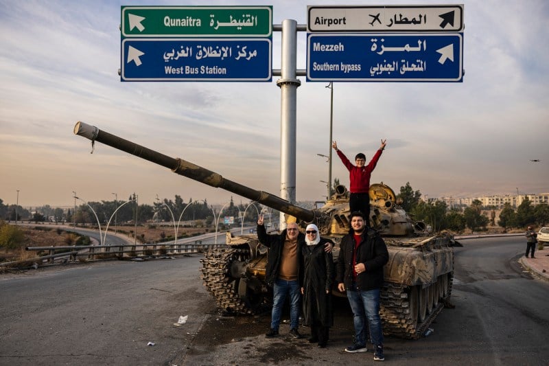 Syrians pose for a picture on a destroyed tank in the Syrian capital of Damascus on Dec. 12.