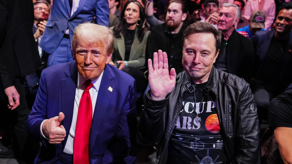 Donald Trump and Elon Musk posing for the camera. Trump in a navy suit and red tie, Musk in a leather jacket and space themed black t shirt.