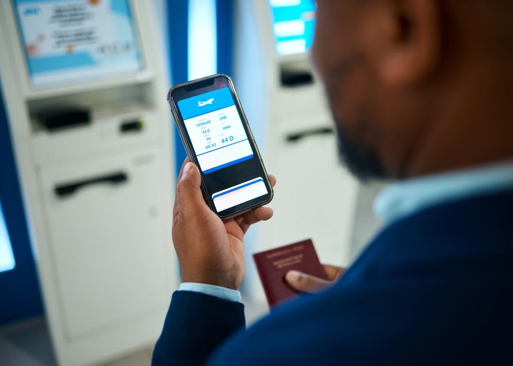 Man at airport booking online ticket on his phone.