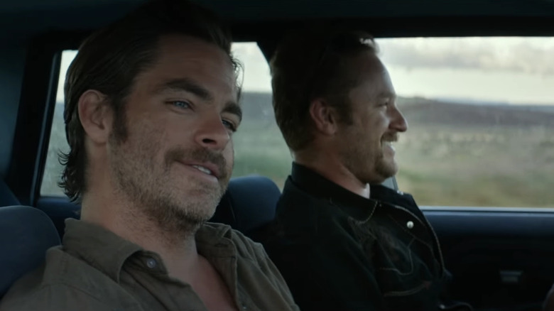 Chris Pine's Toby Howard smiles as he sits alongside Ben Foster's Tanner Howard in the passenger seat of a car in Hell or High Water