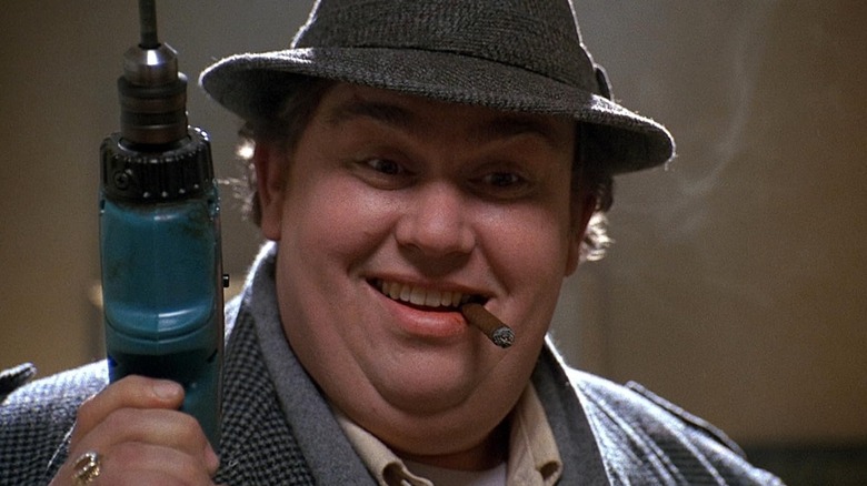 John Candy's Buck Russell holding a drill with a cigar in his mouth in Uncle Buck