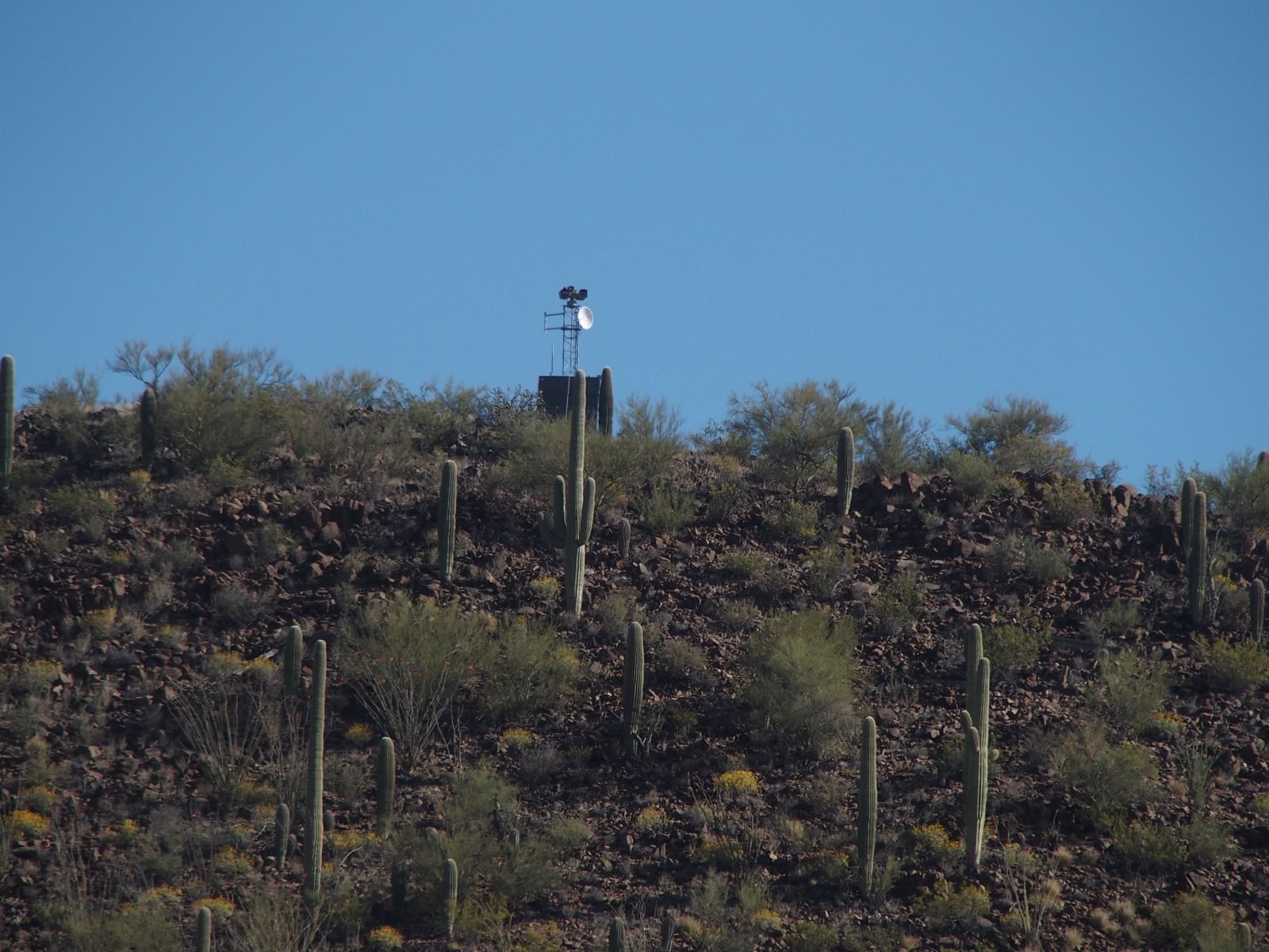 A zoomed-in image of a surveillance tower on a desert hill. 