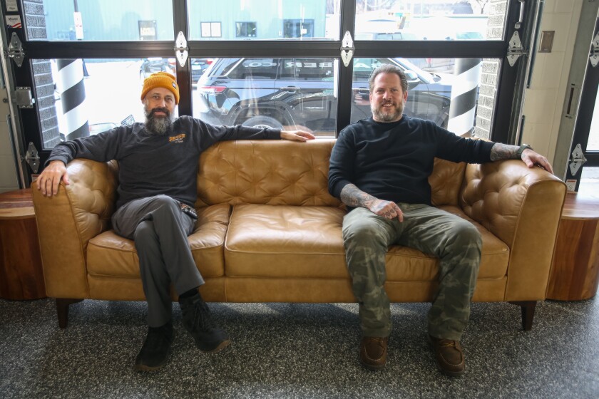 Jade Nielsen, left, and Branden Ashmore, two of the owners of Nice Barber Company, relax on a couch Monday, Jan. 6, 2025, 2024, in the barbershop's new location at 1320 1st Ave. N. in Fargo. 