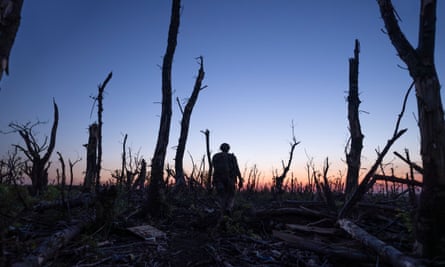 a soldier walks across a landscape of destruction