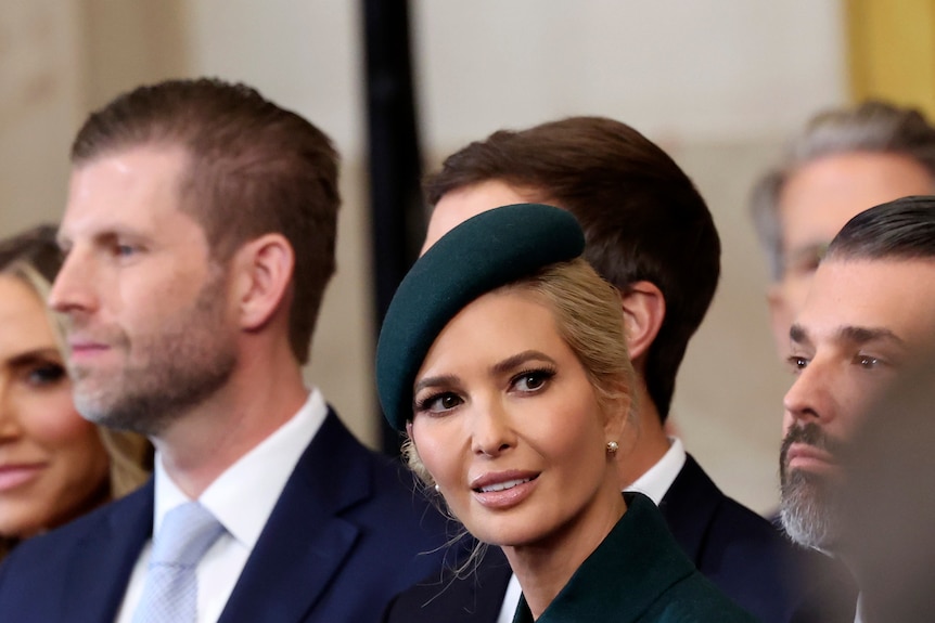 Eric Trump stands to the left of Ivanka Trump, wearing a green hat tilted on the top and side of her head.