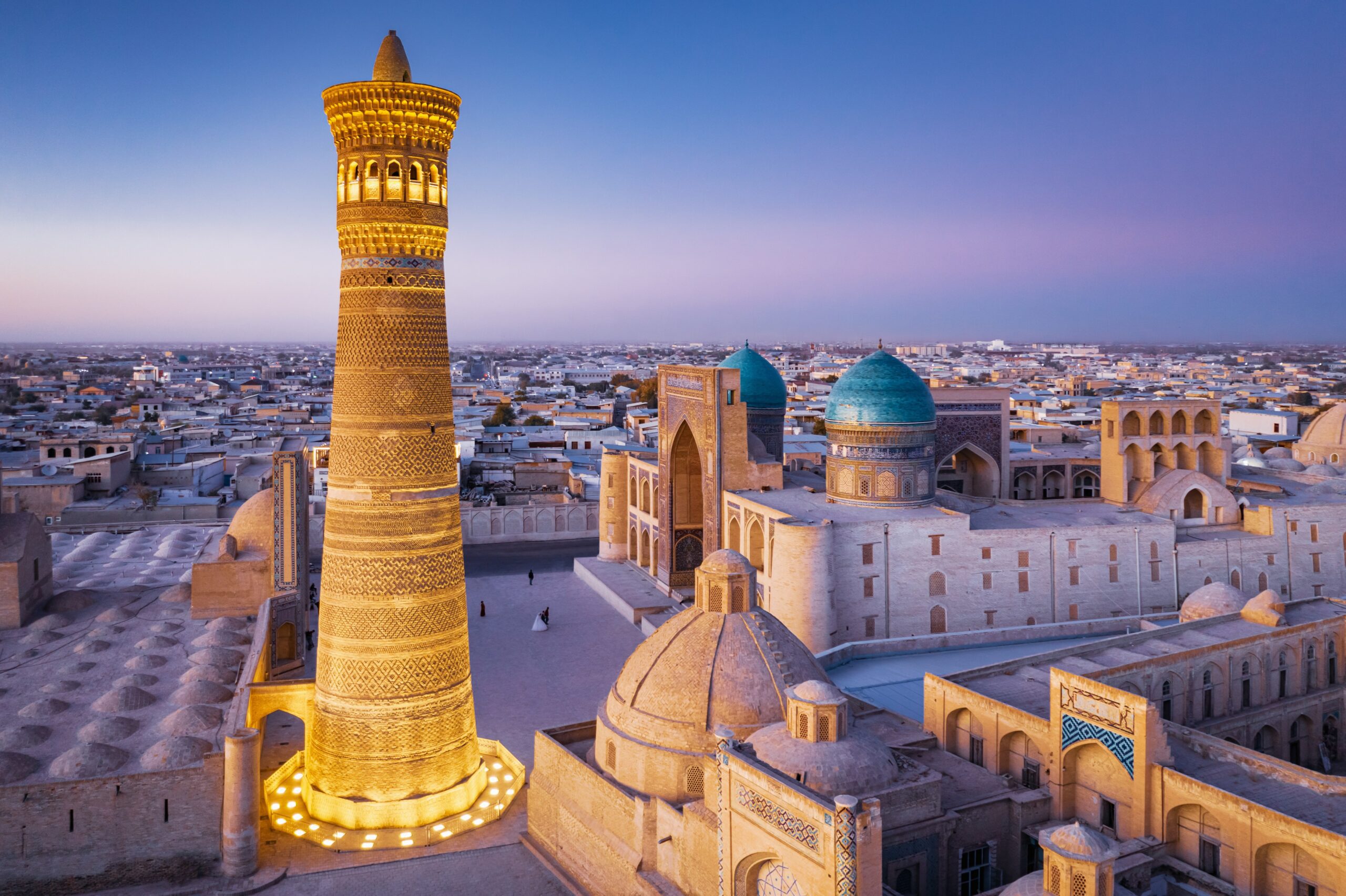 Aerial view of Bukhara, Uzbekistan at sunset, featuring the Kalyan Minaret and Miri Arab Madressa.