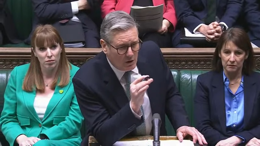 Prime Minister's Questions; a man speaks, flanked by two women.