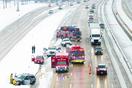 Red trucks on side of snowy highway and two cars in divider.