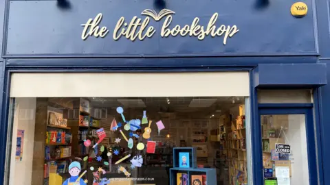 Hannah Limming A shop front with dark blue exterior and a white sign reading: The Little Bookshop