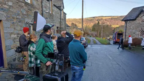 John Argo/The Watermill Crew members set up in the street outside the café while producer Caprice looks around.