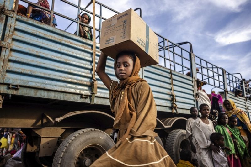 A refugee from the war in Sudan carries her belongings after arriving at a transit center for refugees in South Sudan on Feb. 13, 2024.