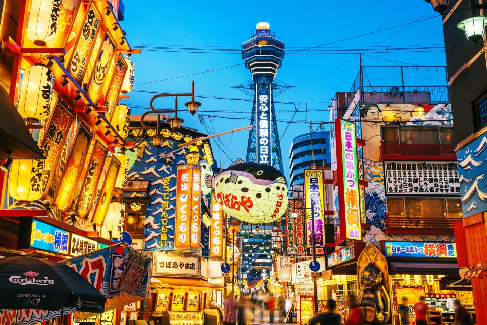 Osaka Tower and Shinsekai district's neon lights at night.