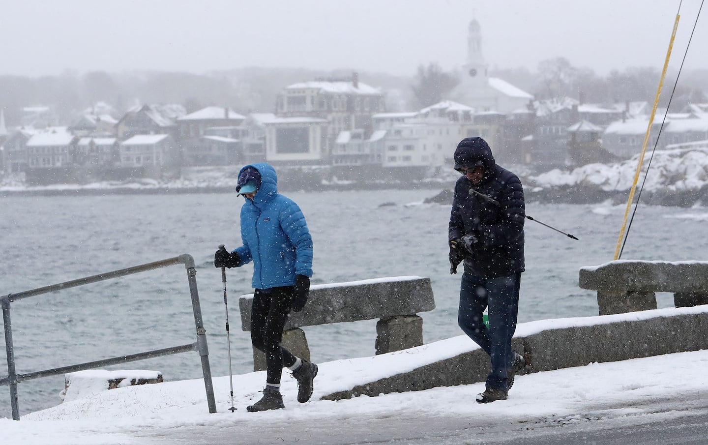 As snow fell, walkers passed Back Beach in Rockport Saturday.