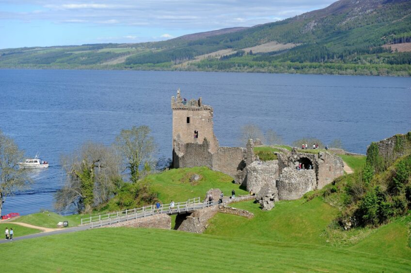 Urquhart Castle on the shore of Loch Ness on a sunny day with Loch Ness stretching out in the background