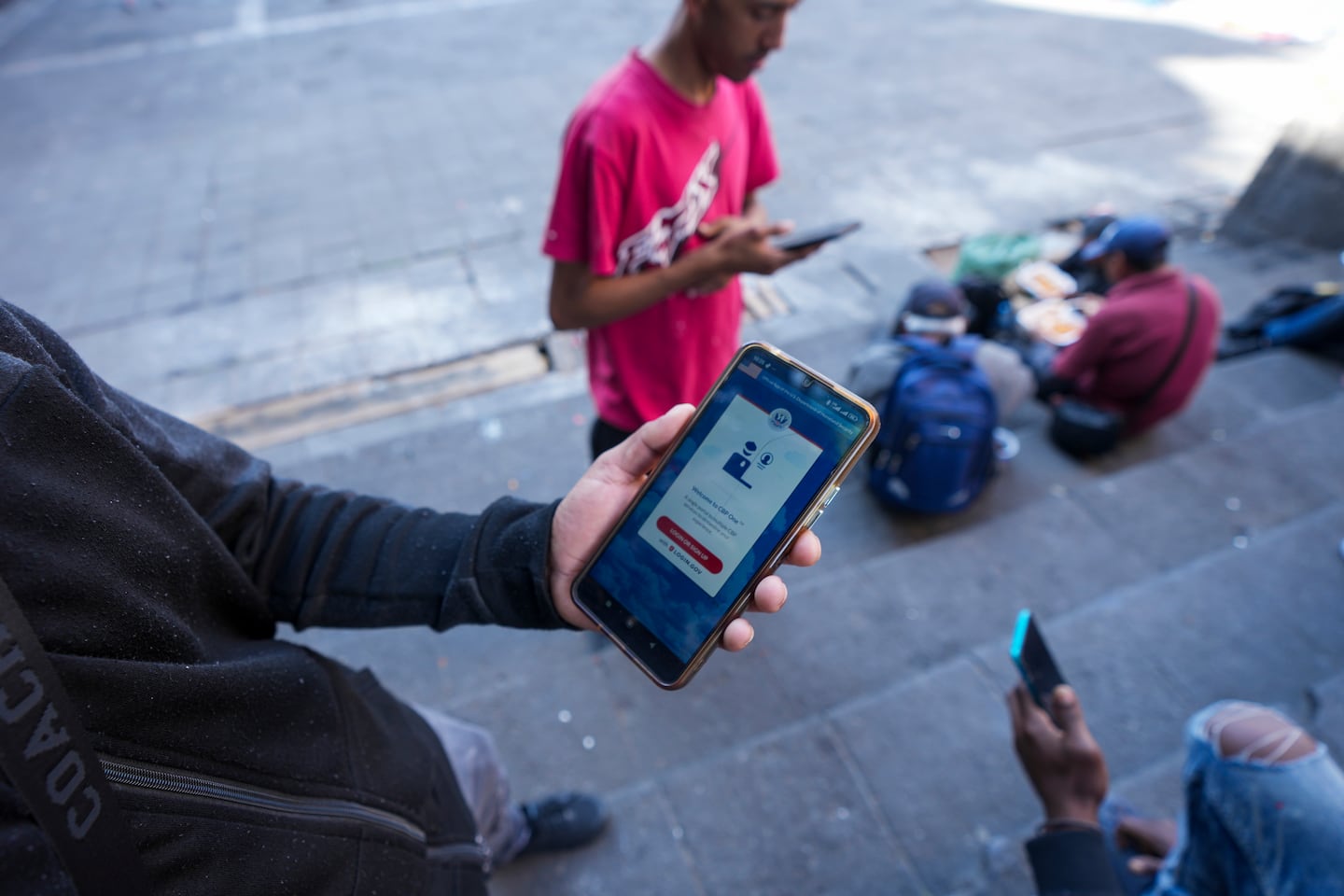 Venezuelan migrant Yender Romero showed the Customs and Border Protection (CBP) One app on his cell phone, which he said he used to apply for asylum in the US and is waiting on an answer, at a migrant tent camp outside La Soledad church in Mexico City on Monday.