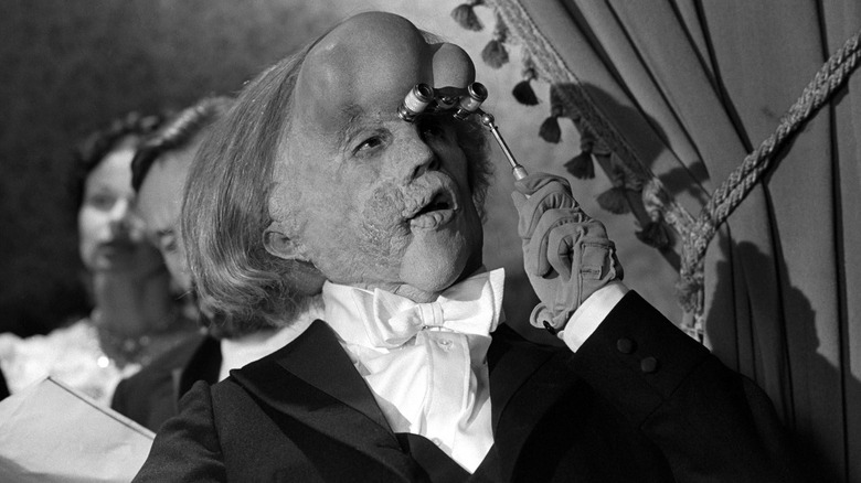 John Hurt as John Merrick views a pantomime through opera glasses in The Elephant Man