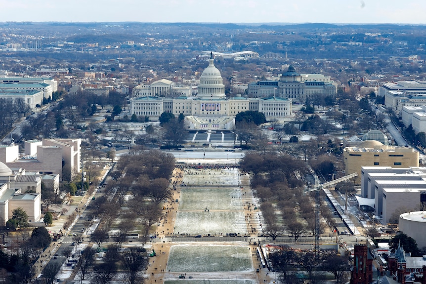 An aerial view of the US Capitol and the National Mall, which is mostly empty and covered in snow.