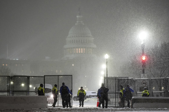 Law enforcement officers stand guard at the Capitol as snow falls ahead of a joint session of Congress to certify the votes for thee 2024 election