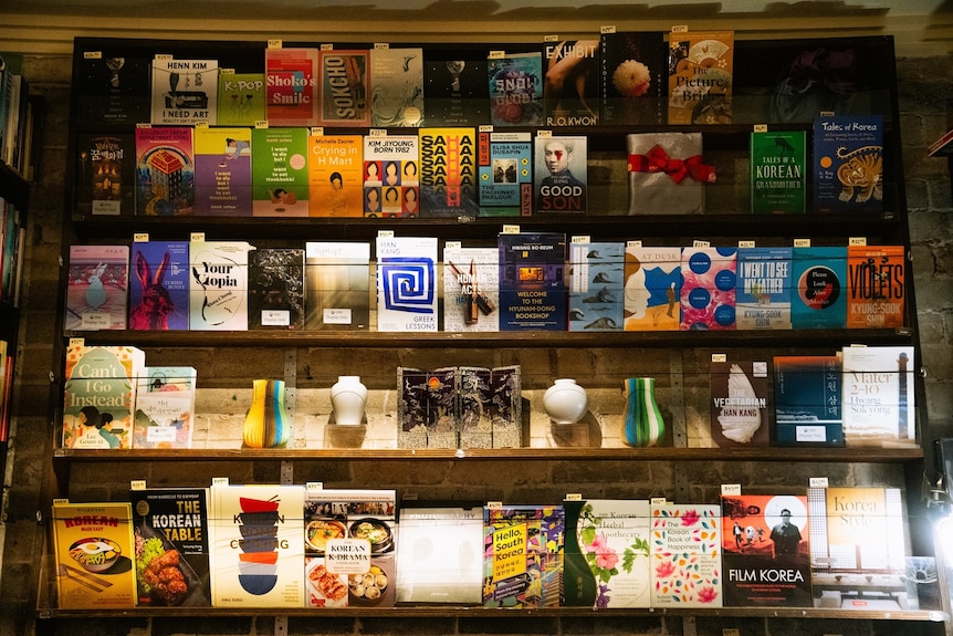 A window with warm yellow lighting showing several books on shelves with covers facing out. 