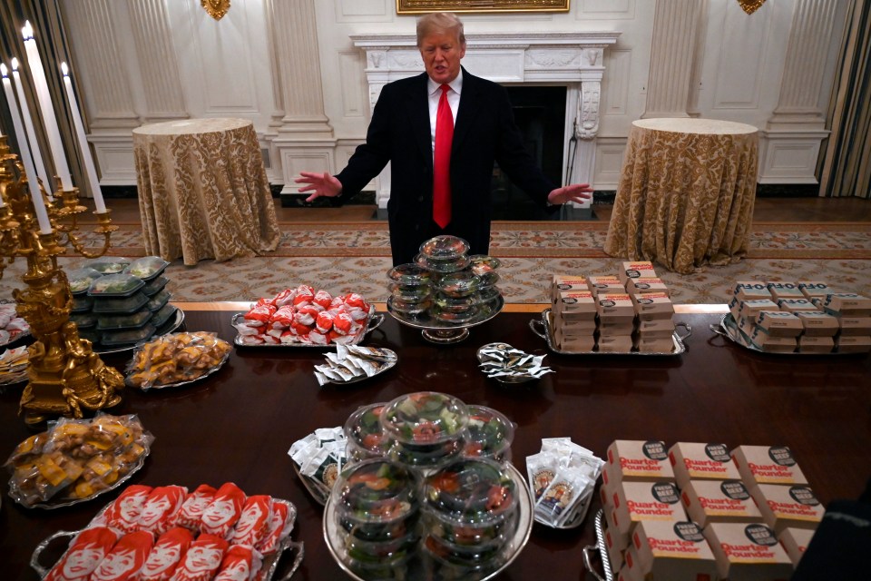 Donald Trump standing in the White House, gesturing towards a table laden with fast food.