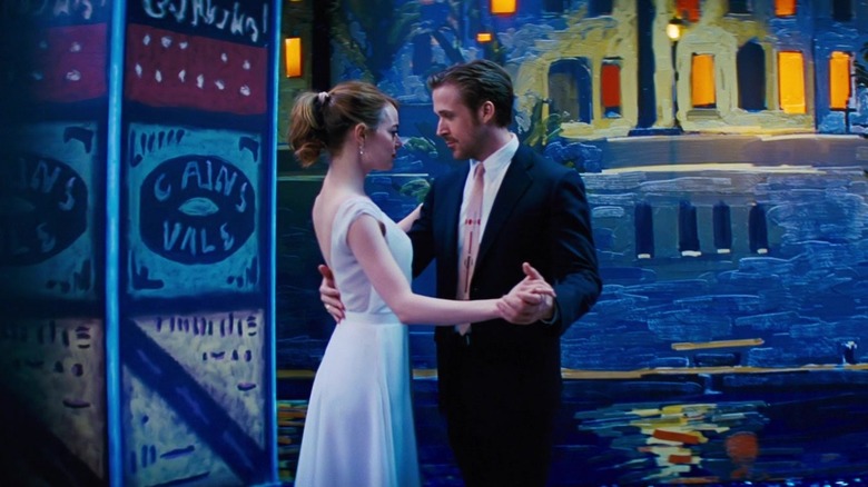 Emma Stone and Ryan Gosling as Mia and Sebastian in a dancer's embrace against a painted backdrop in La La Land