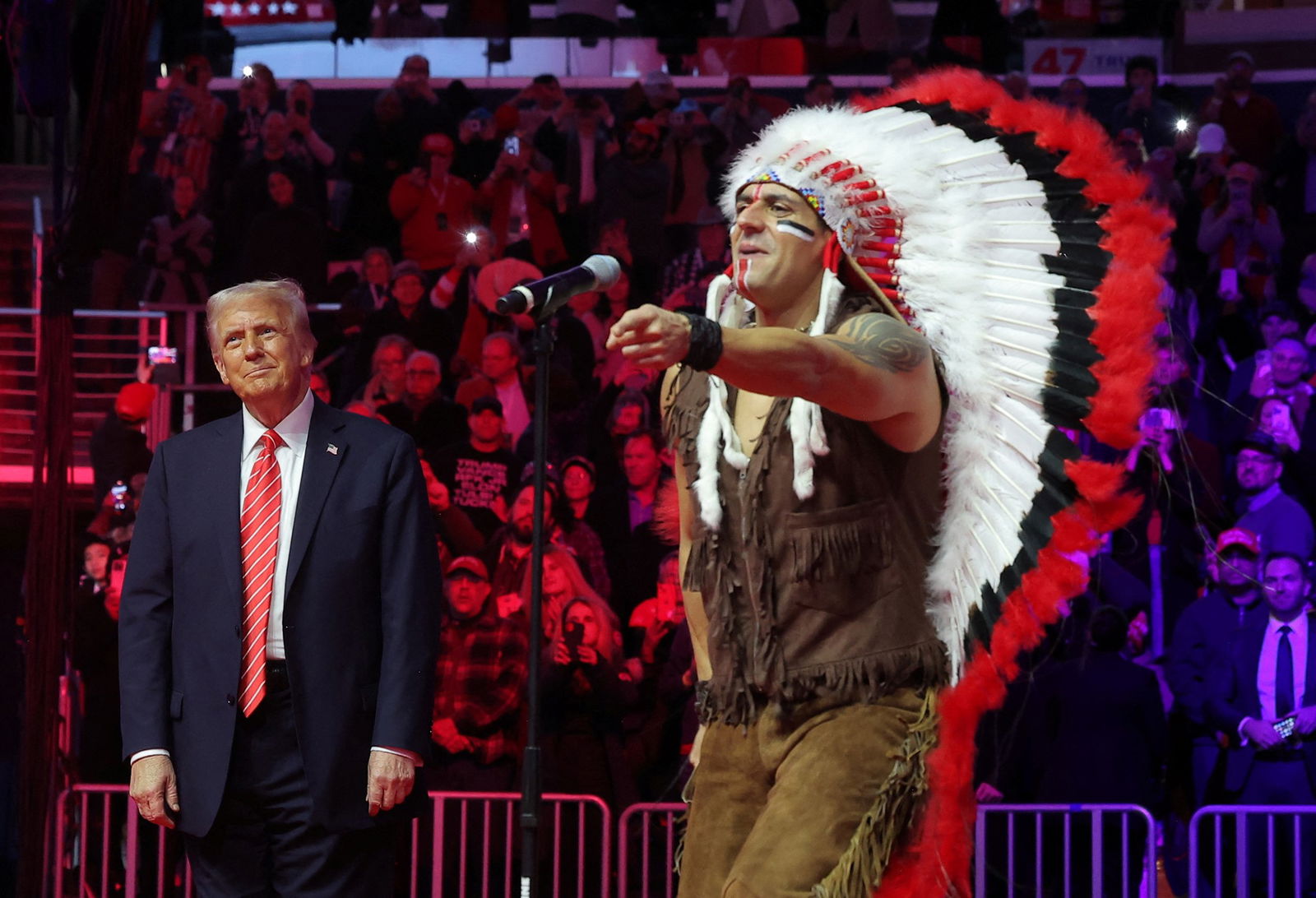 Trump reacts as a member of The Village People dances in a Native American headdress