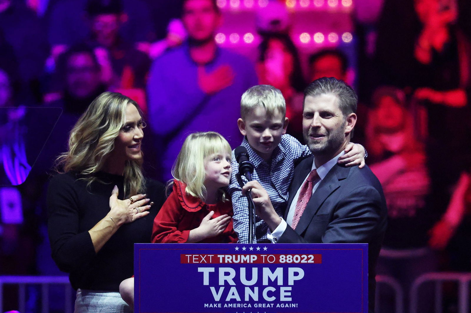 Eric and Lara Trump hold their young children up to reach a podium microphone.