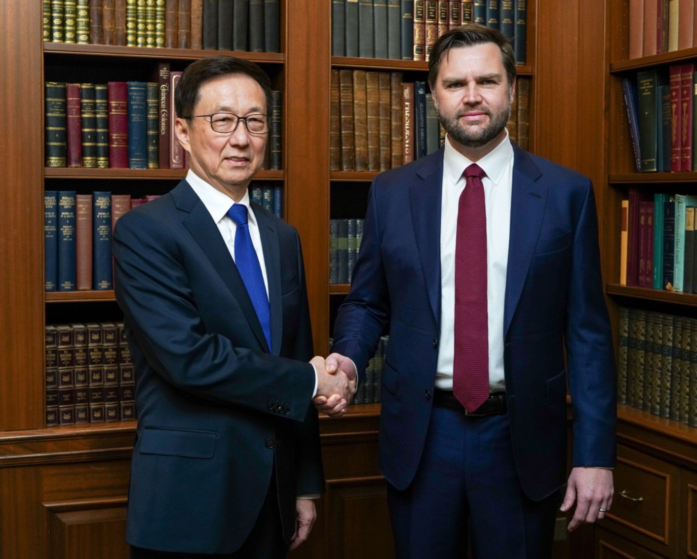 Han Zheng and JD Vance shake hands in front of a bookshelf