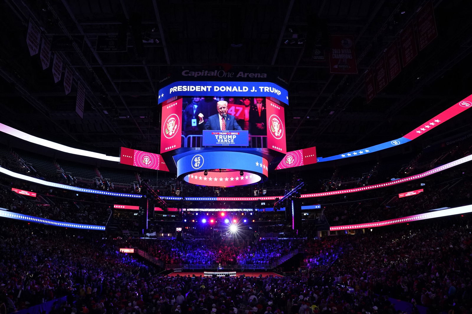 A view of the Capital One Arena filled with crowds. Trump can be seen speaking through a screen overhead