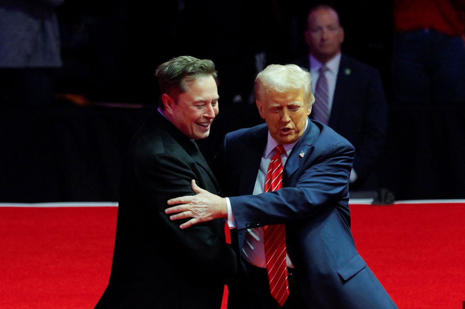 Musk and Trump embrace on a red stage