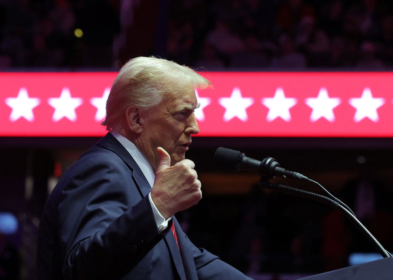 Donald Trump hitches a thumb as he speaks into a microphone