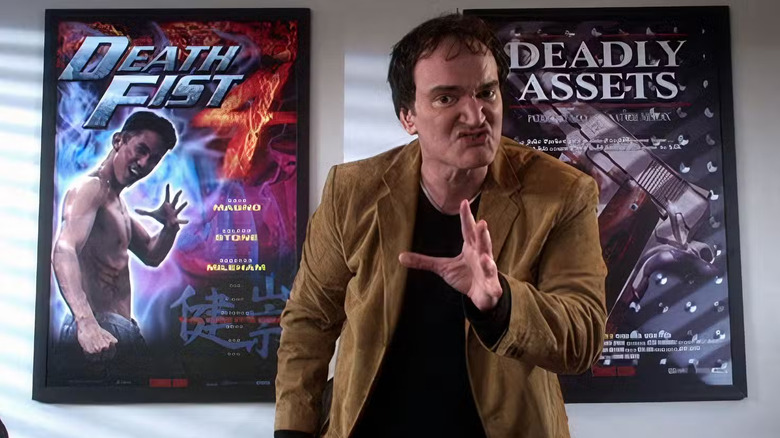 Quentin Tarantino standing in front of two action movie posters in The Muppets' Wizard of Oz