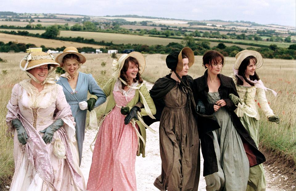 The cast of Pride & Prejudice walking in a field.