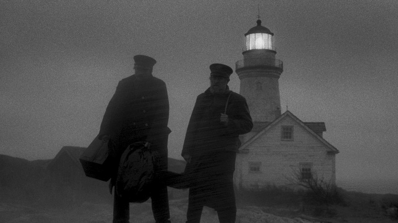 Winslow and Wake stand in front of the lighthouse in The Lighthouse