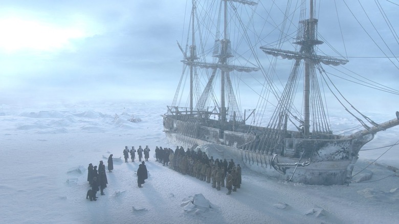 The crew of the Terror stand on the ice by the trapped ship in The Terror