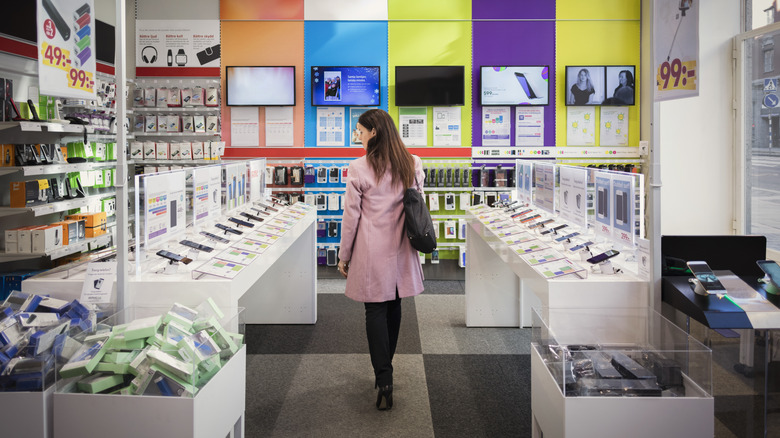 A woman standing in an electronics items store.