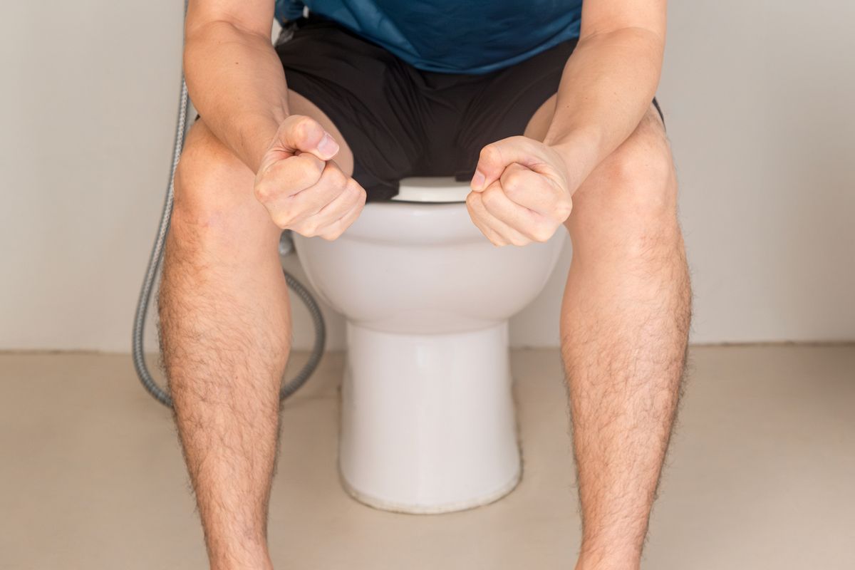 Man sits on the toilet bowl in the bathroom, he has stomach ache and bad digestive system. Constipation. Diarrhea. Food poisoning. health and medicine.