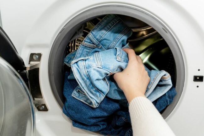 0_Person-putting-jeans-into-the-drum-of-a-washing-machine-front-view-Washing-dirty-jeans-in-the-wash.jpg