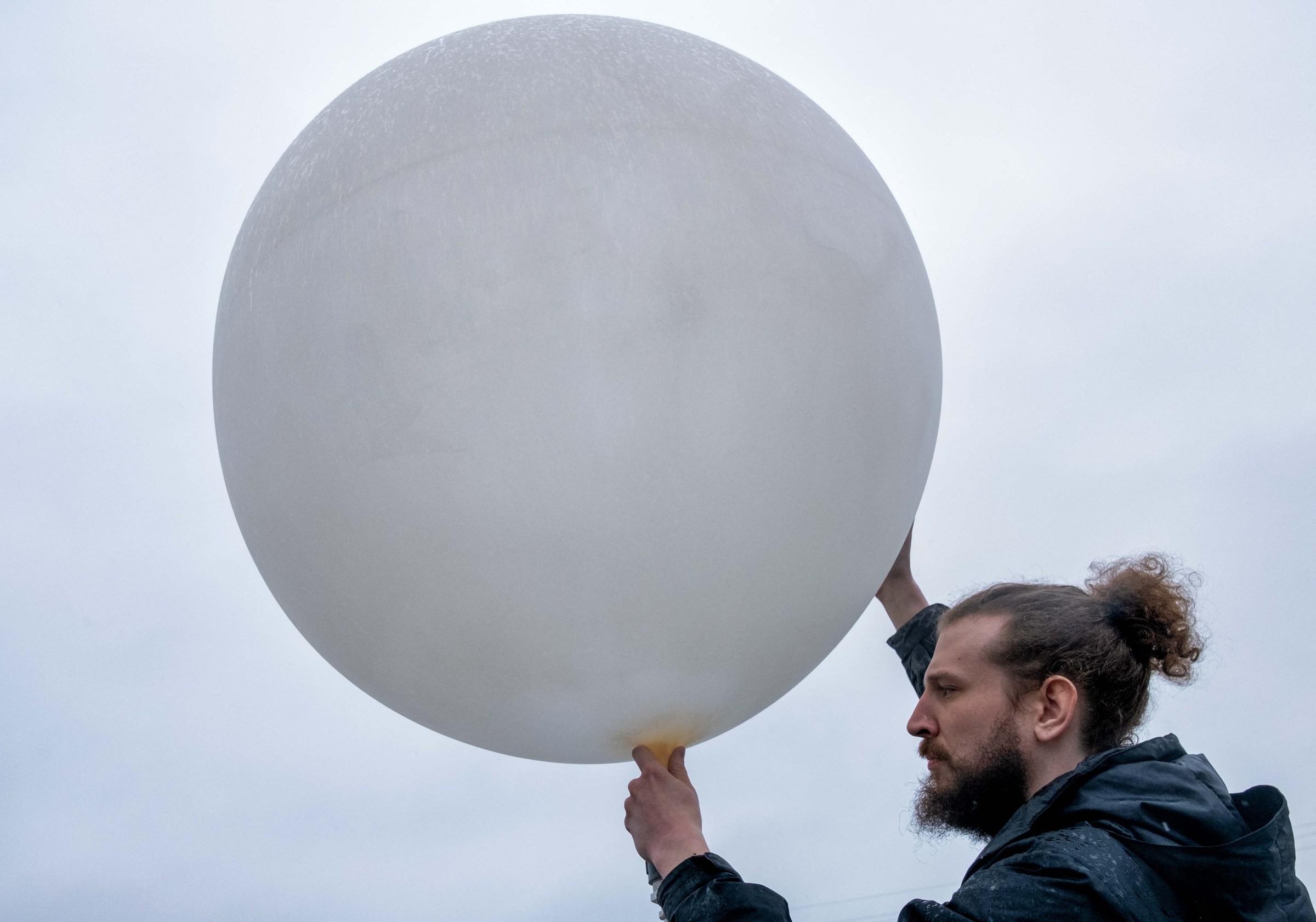 A member of a weather team prepares a weather balloon for release