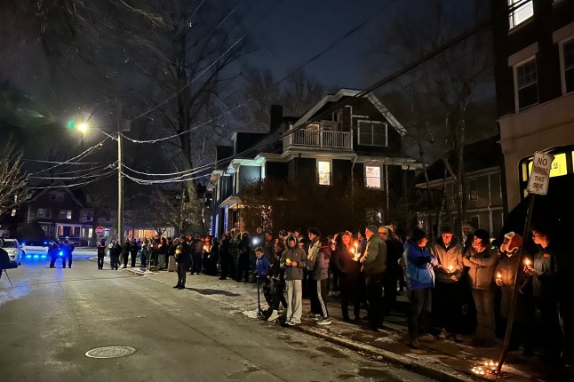 A crowd of people holding candles gather outside the home of Massachusetts Institute of Technology professor Nuno F.G. Loureiro in Brookline, Mass., Tuesday, Dec. 16, 2025. (AP Photo/Leah Willingham)
