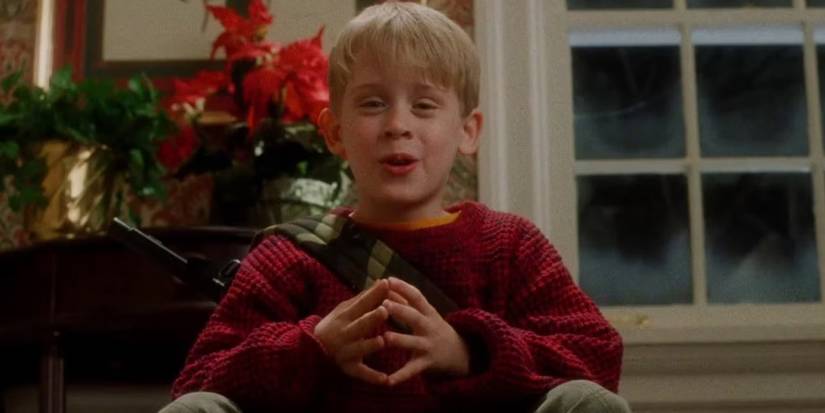 Kevin sitting on the stairs smiling in Home Alone