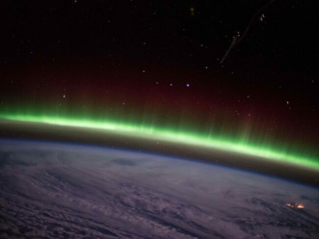 A-green-auroral-arc-appears-above-the-clouds-in-this-photo-taken-by-an-astronaut-aboard-the-International-Space-Station-in-2014..jpg